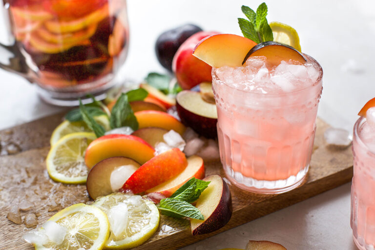 image of plums and ingredients on cutting board with glass of white wine plum sangria